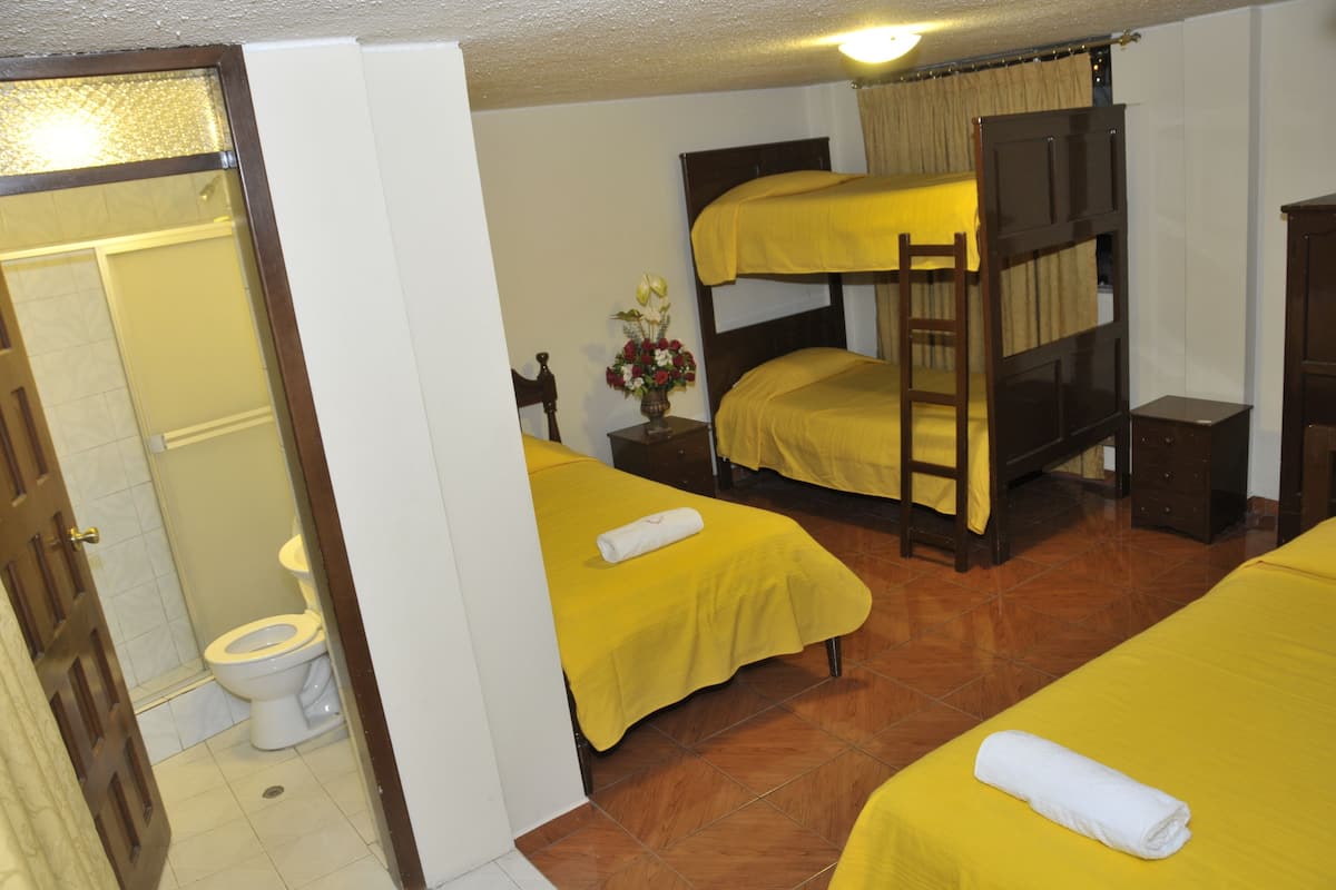 A hotel room with two beds, a bathroom, and a wooden bunk bed.