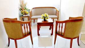 A room with a sofa, two armchairs, and a small table with a vase of flowers. - Hotel Margarita 2 (Quito)