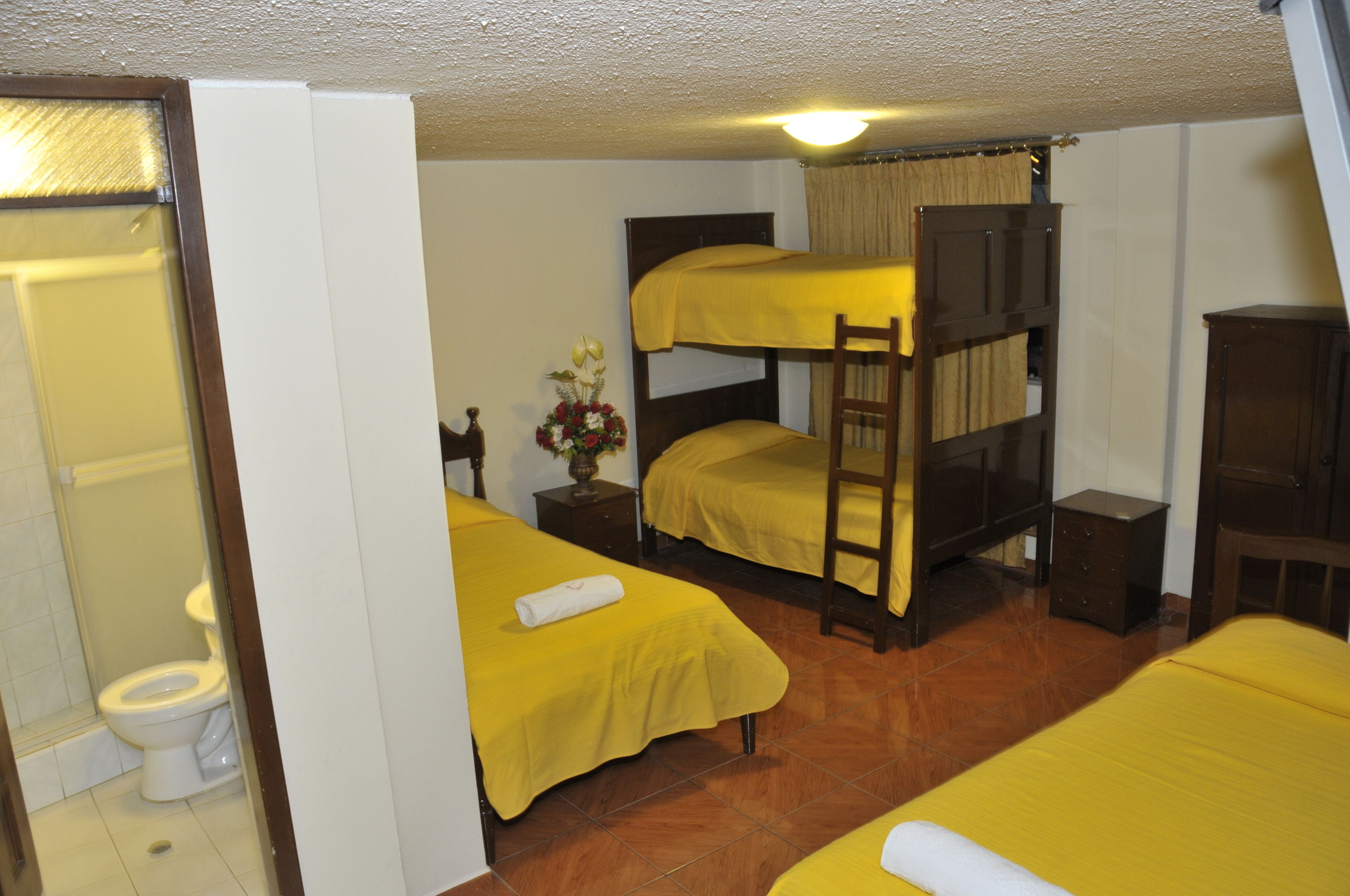 Una camera del dormitorio con letti a castello, un comodino con una lampada e un bagno con il water e la doccia.