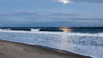 A beach with waves and a cloudy sky.