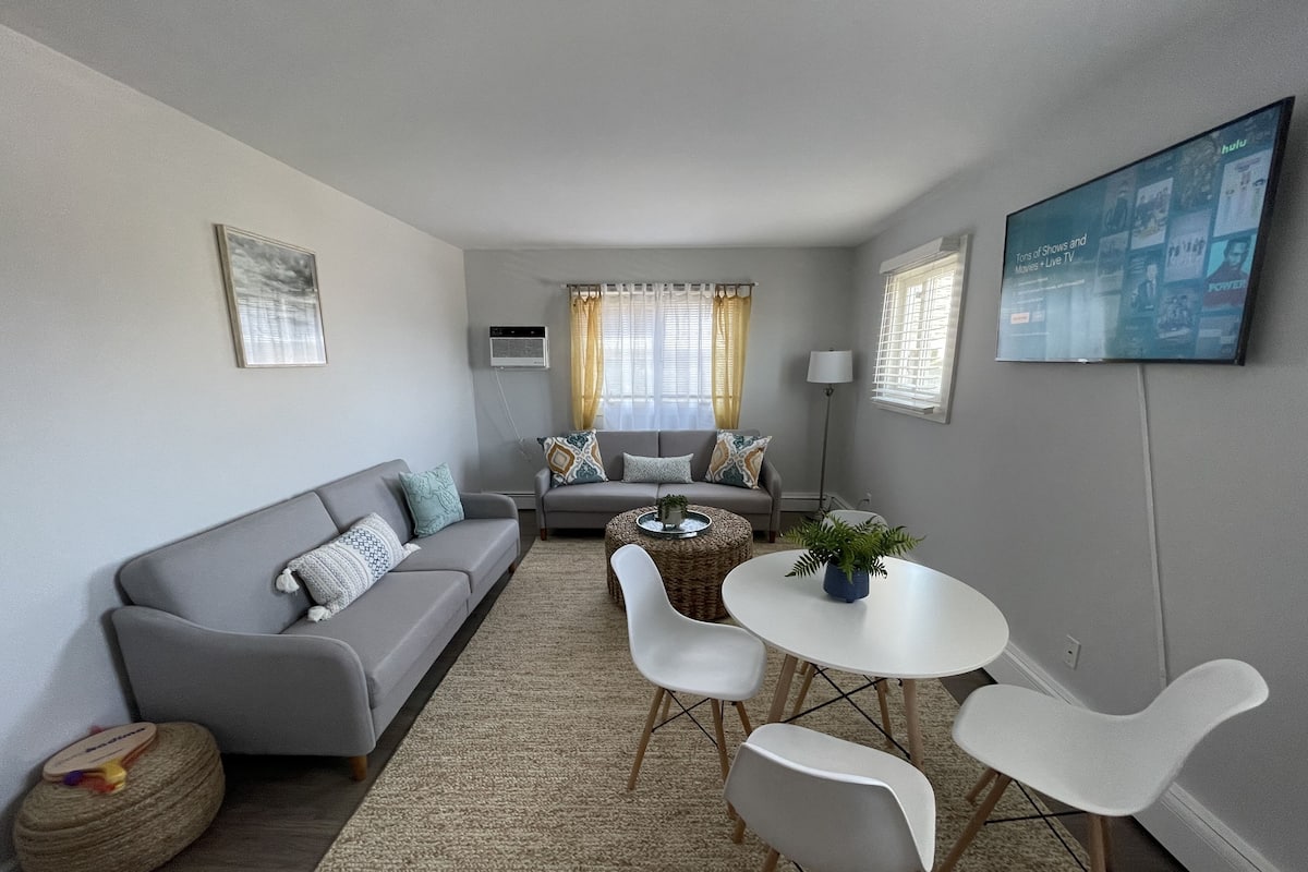 A modern living room with a grey sofa, a coffee table, and a TV mounted on the wall.