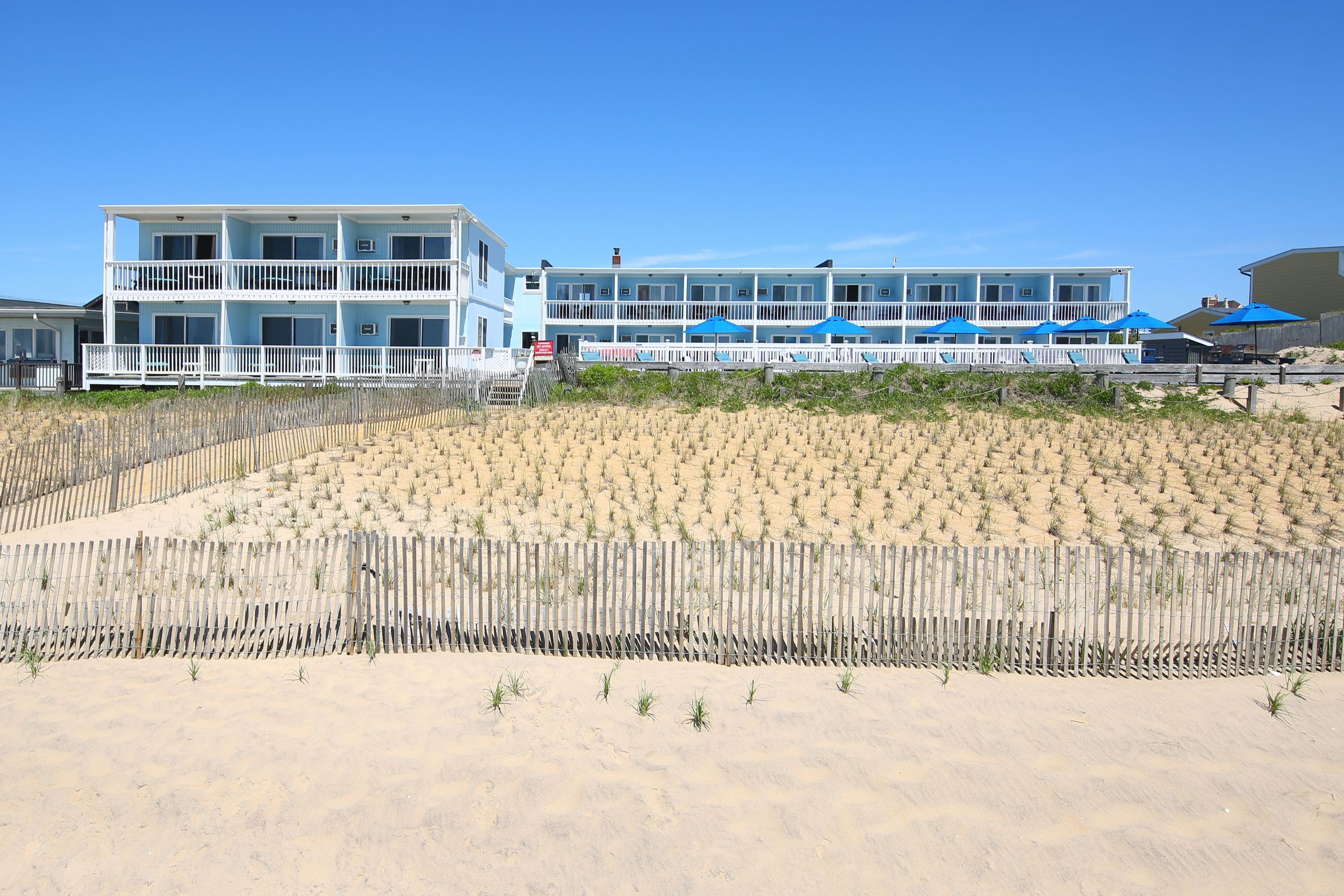 Hotel à beira-mar com várias varandas e uma praia de areia em primeiro plano.