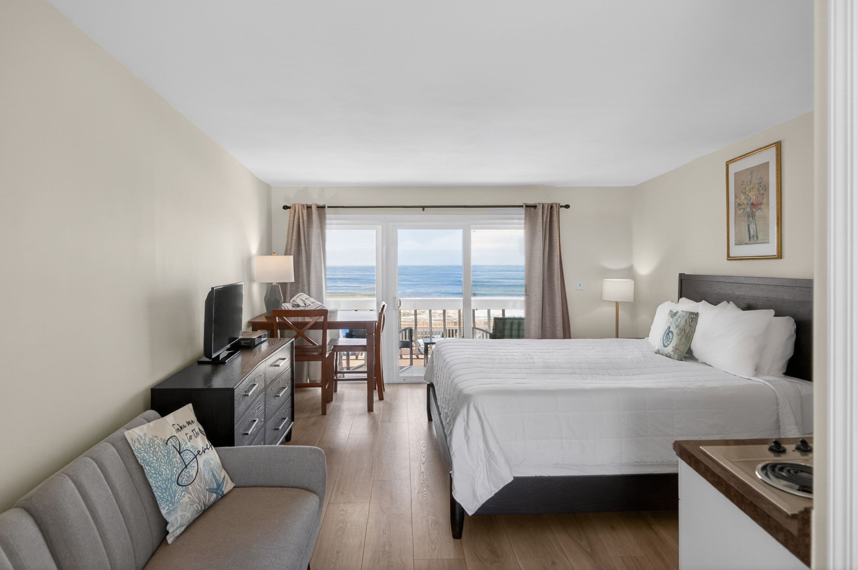 Habitación de hotel con cama, televisión, escritorio y vista al océano.