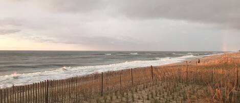 A beach with a wooden fence and waves crashing onto the shore.