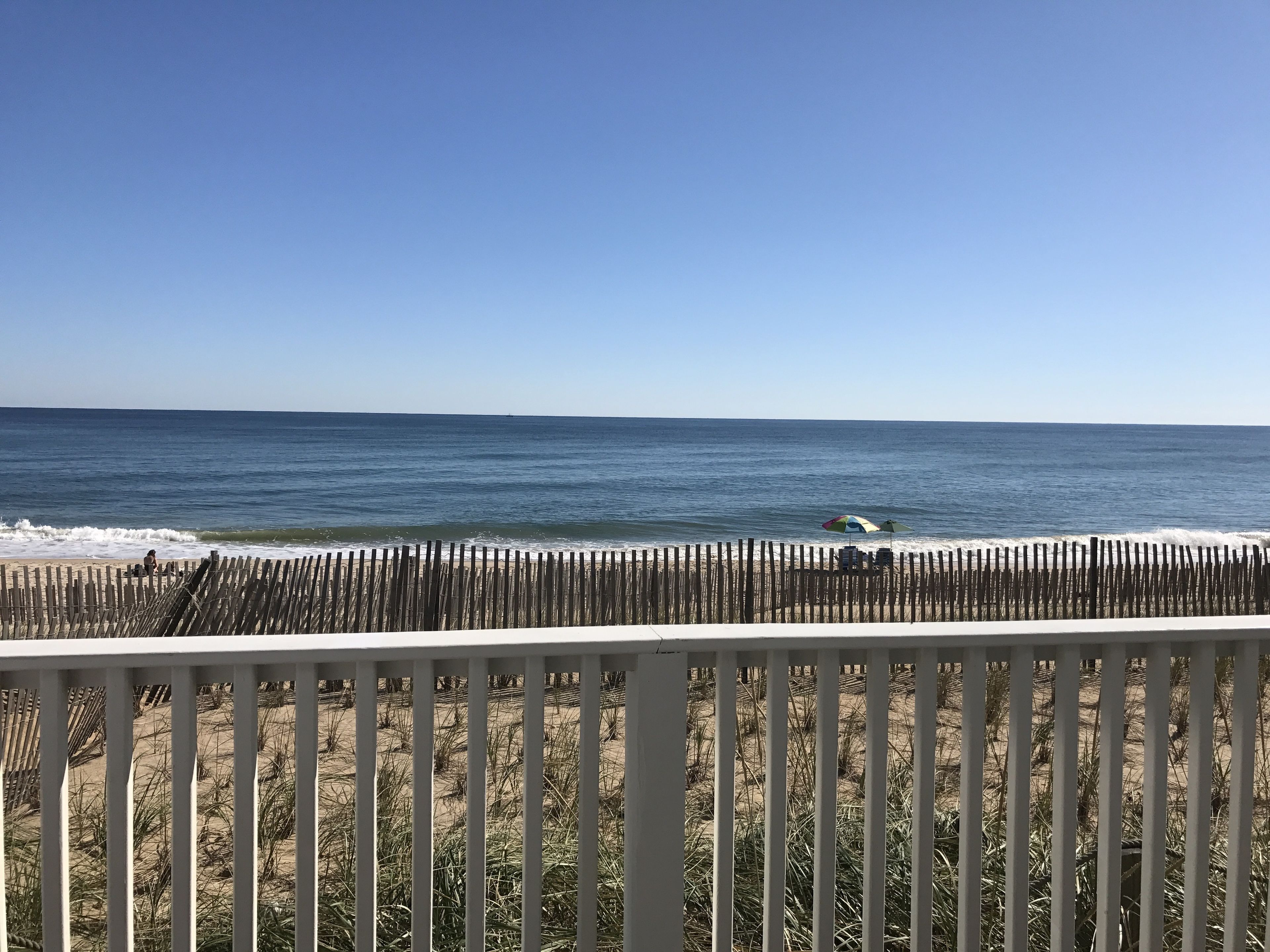 Vista a la playa con una valla de madera, arena y océano.