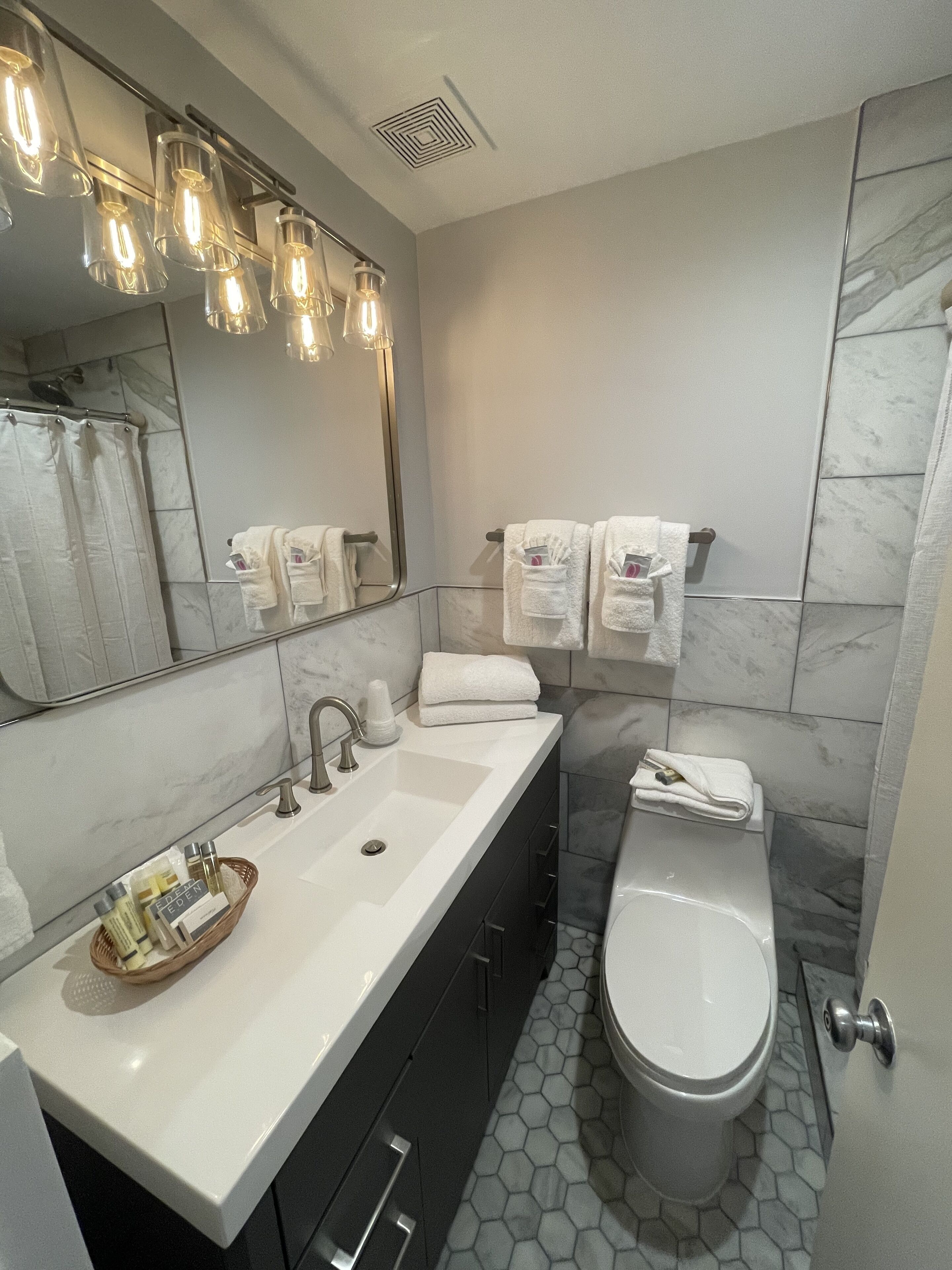 Une salle de bain moderne avec un grand miroir, un lavabo, des toilettes et une douche.