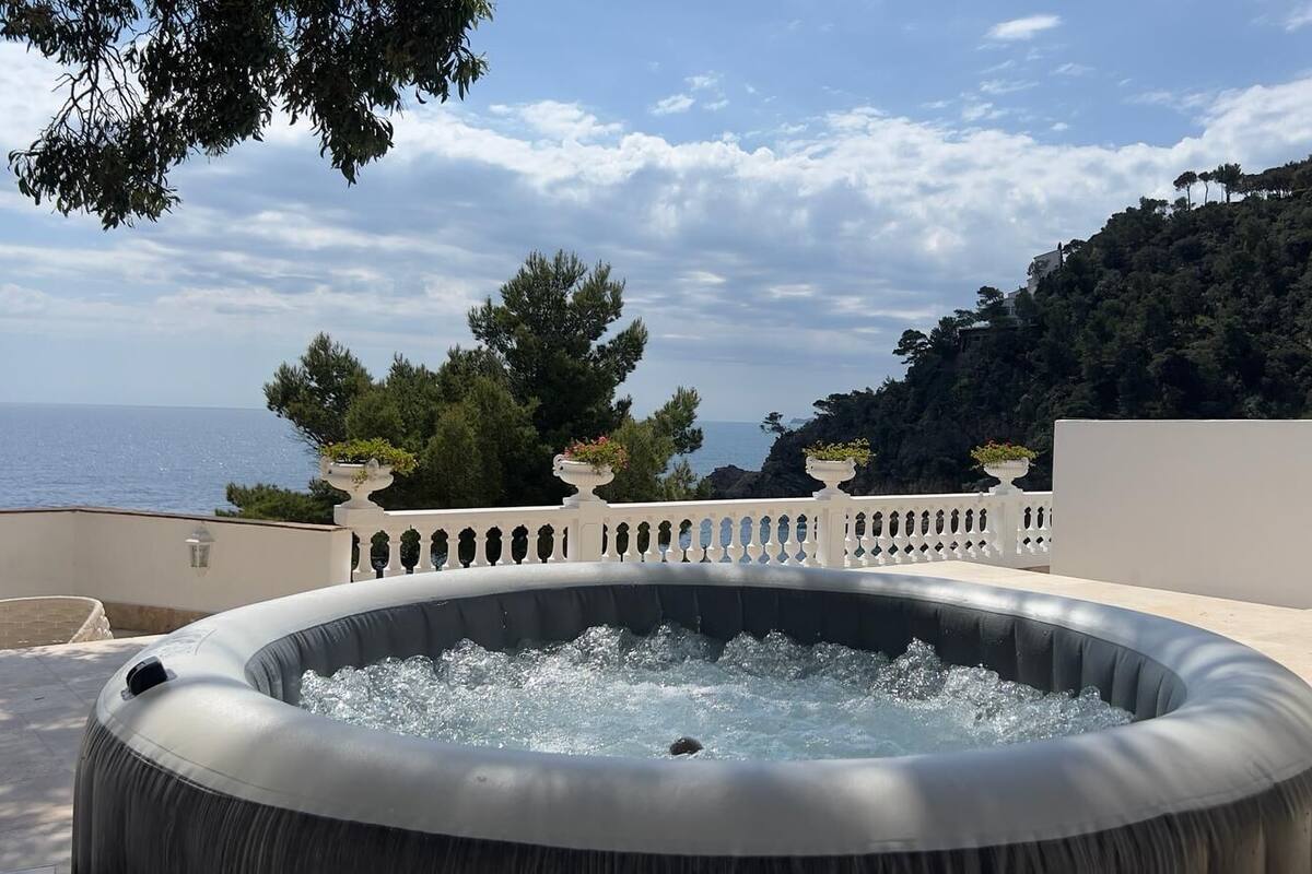 Un jacuzzi en una terraza con vista al mar y un paisaje montañoso.