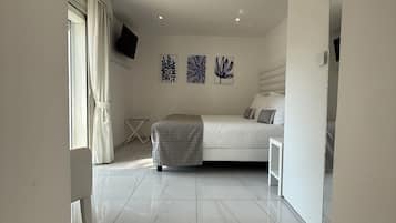 Une chambre à coucher moderne avec un lit, un téléviseur fixé au mur et des œuvres d’art.