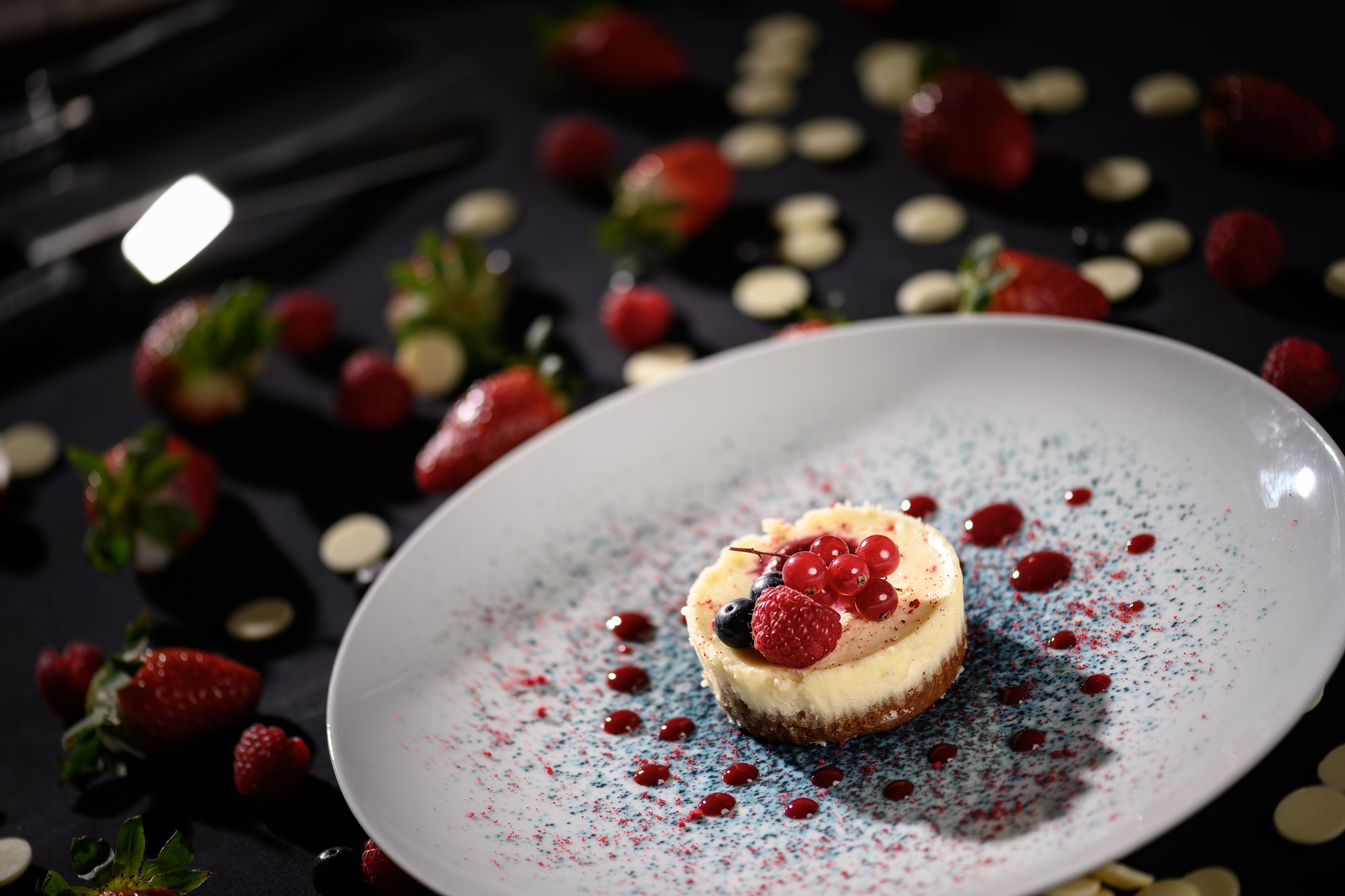 Un dessert présenté sur une assiette, entouré de fraises et d’autres baies.