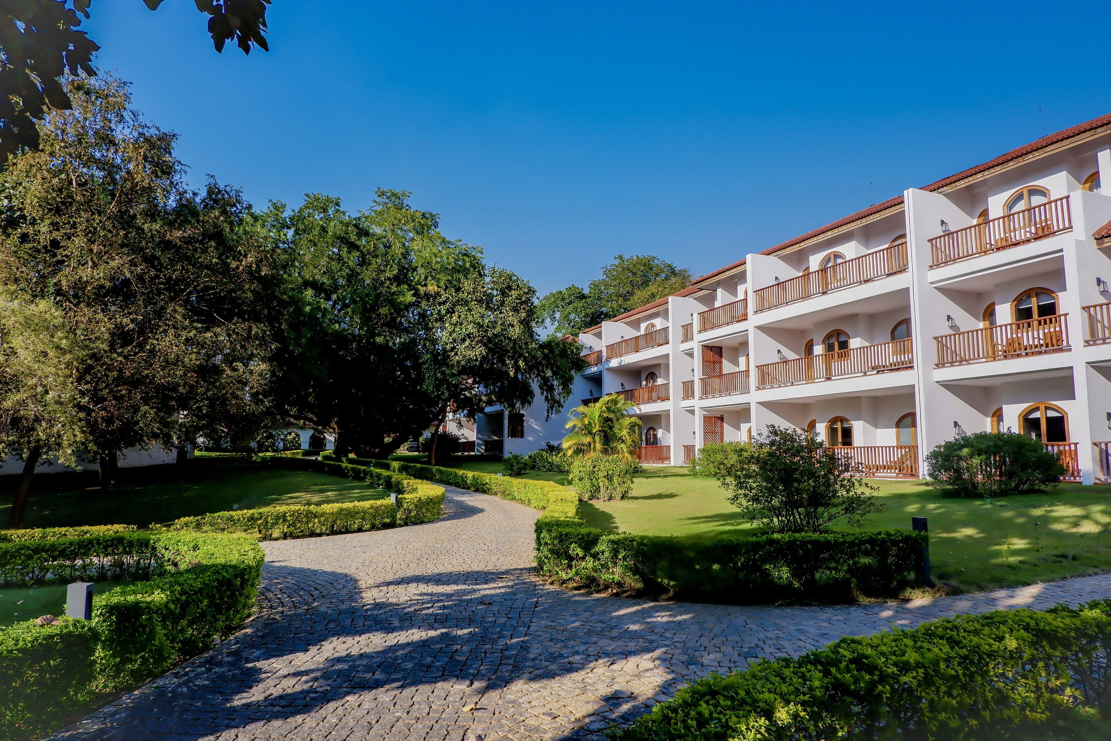 A multi-story hotel with a courtyard, cobblestone pathway, and well-maintained greenery.