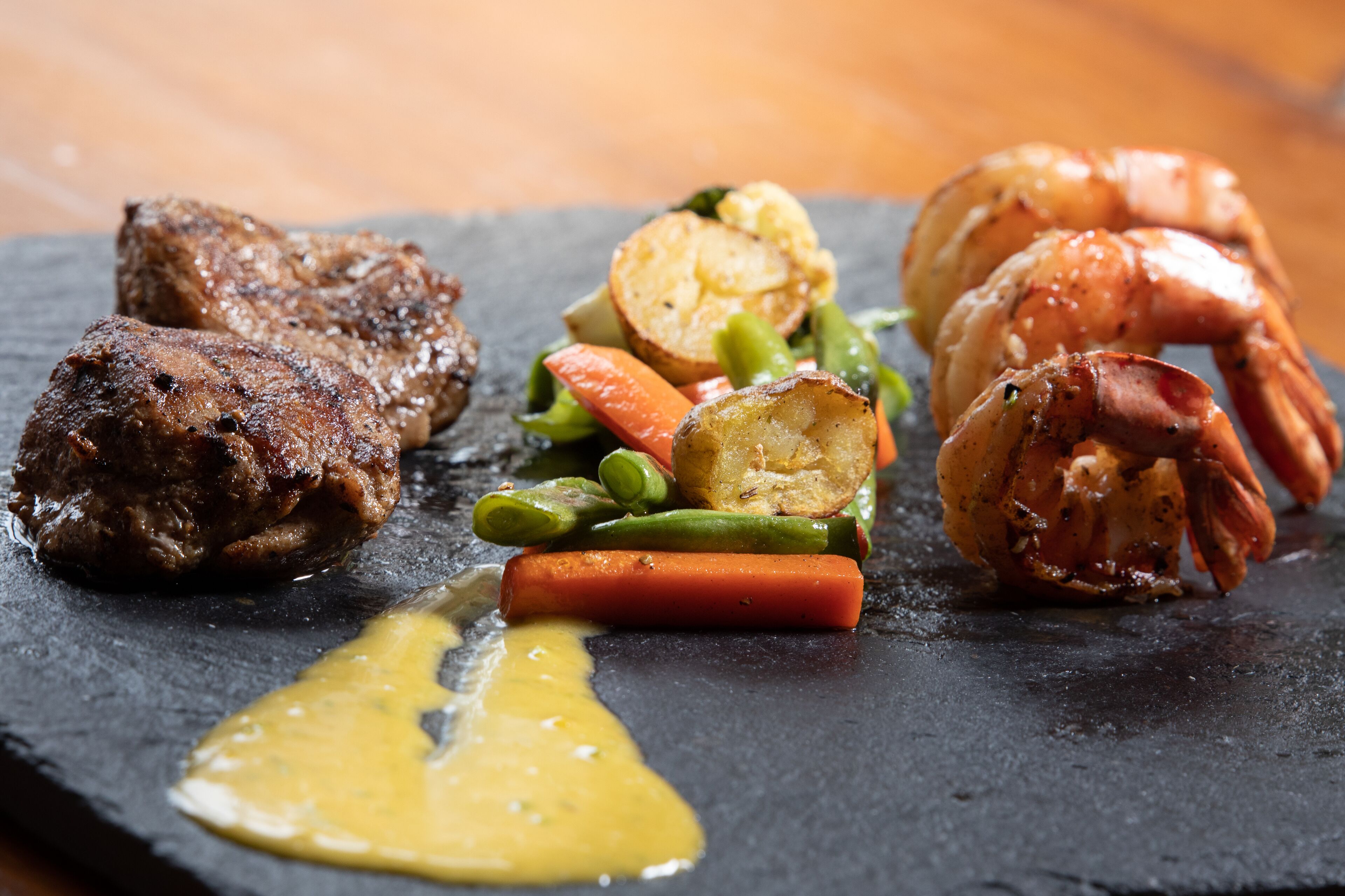 A plate of food with steak, shrimp, and vegetables.