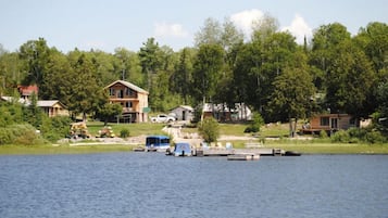 Une propriété au bord du lac, dotée d’un quai, de bateaux et de maisons entourées d’arbres.