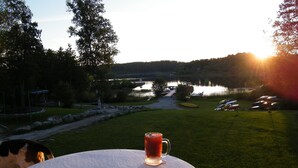 A table with a mug of beverage, a grassy area, a lake, and boats in the background.