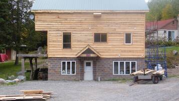 Une maison en bois à deux étages, avec des fondations en briques, un porche à l’avant et un garage.