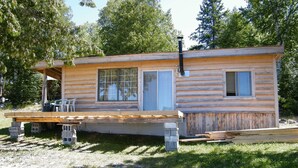 A rustic cabin with a porch, a window, and a chimney.