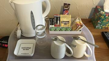 A tray with a white kettle, a glass, two white mugs, a spoon, a box of Nescafé Original instant coffee, a pack of Yorkshire Gold tea, and a box of Nestlé milk.