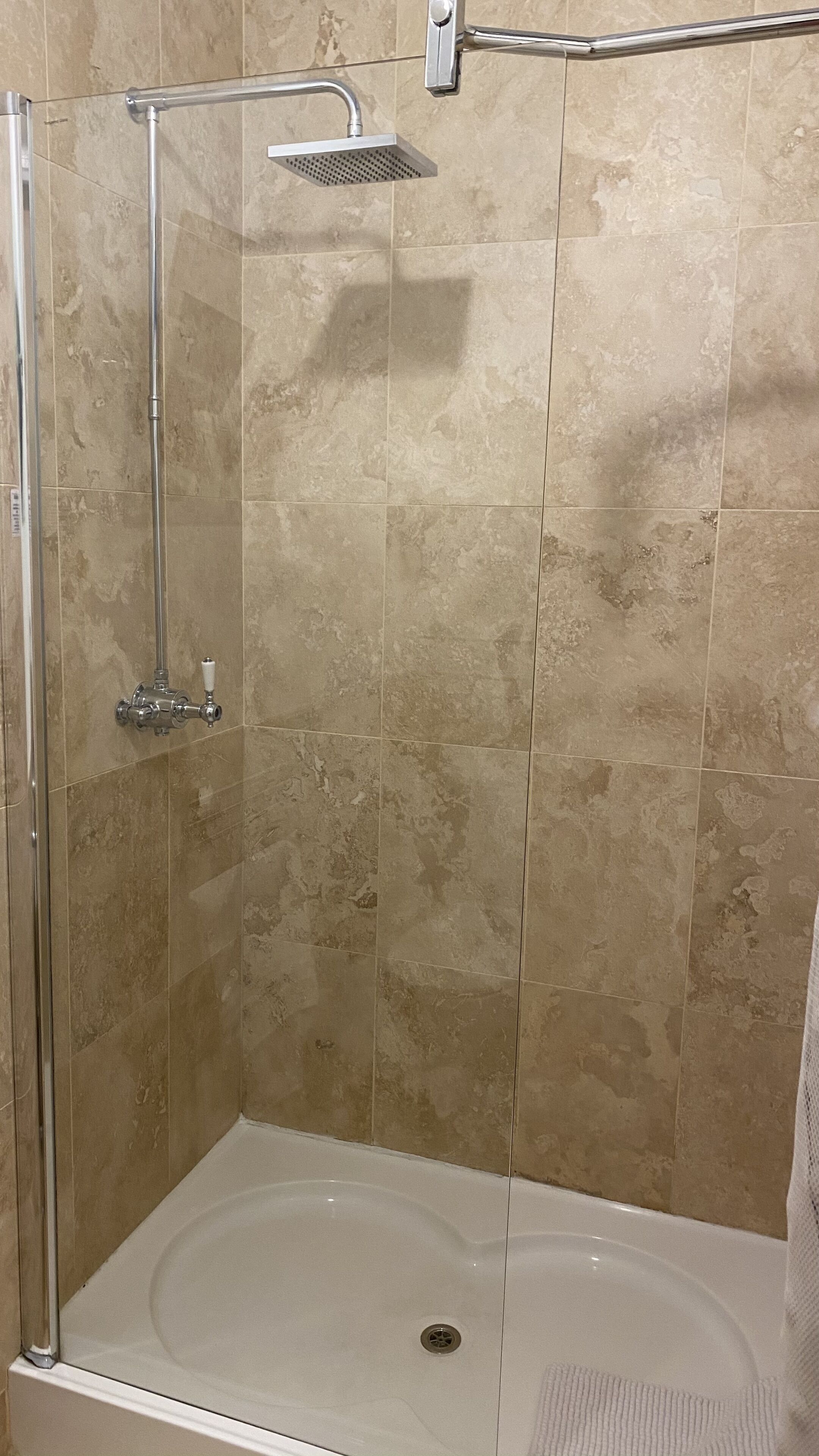 A walk-in shower with a handheld showerhead, a handheld showerhead, and a control valve.