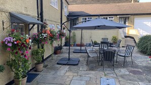 A patio area with stone flooring, outdoor furniture, and potted plants. - Bridge Farm Hotel (Leeds)