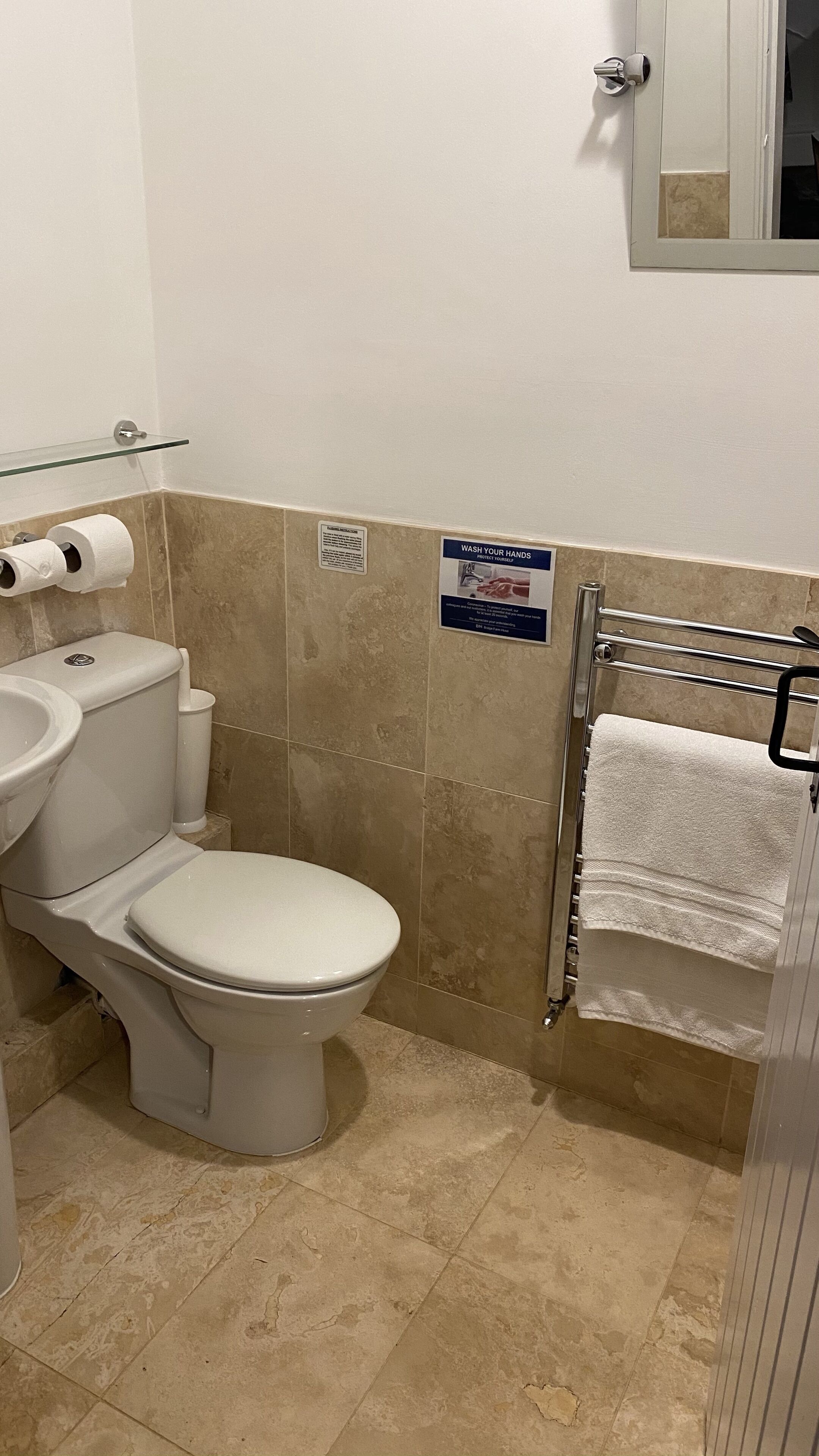 Un baño con inodoro, lavamanos y perchero para toallas.