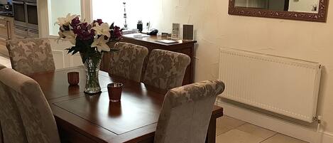 A dining area with a wooden table, six chairs, and a vase of flowers.