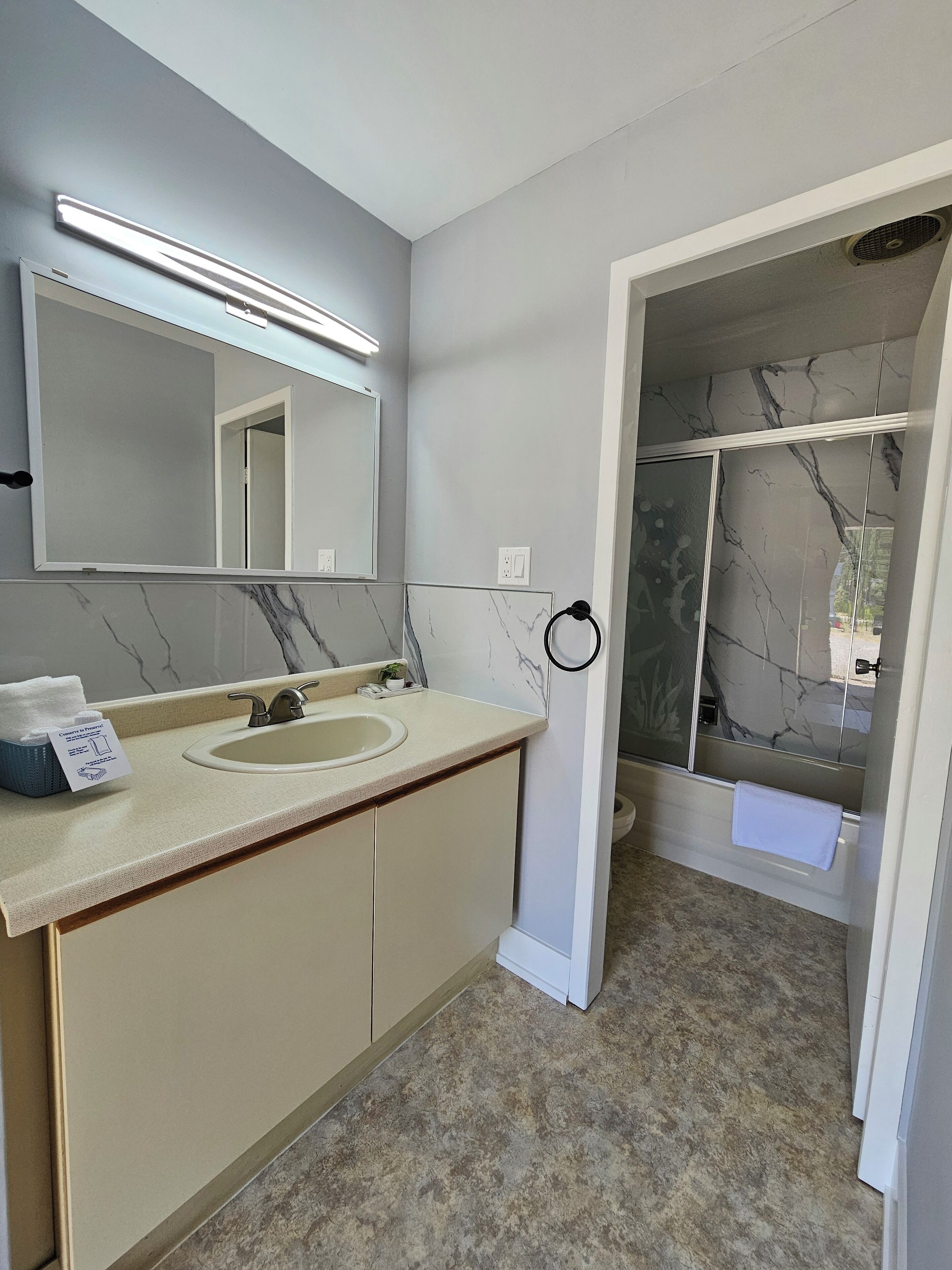 Une salle de bain avec un mur recouvert de carreaux de marbre, un lavabo avec un miroir et un espace douche.