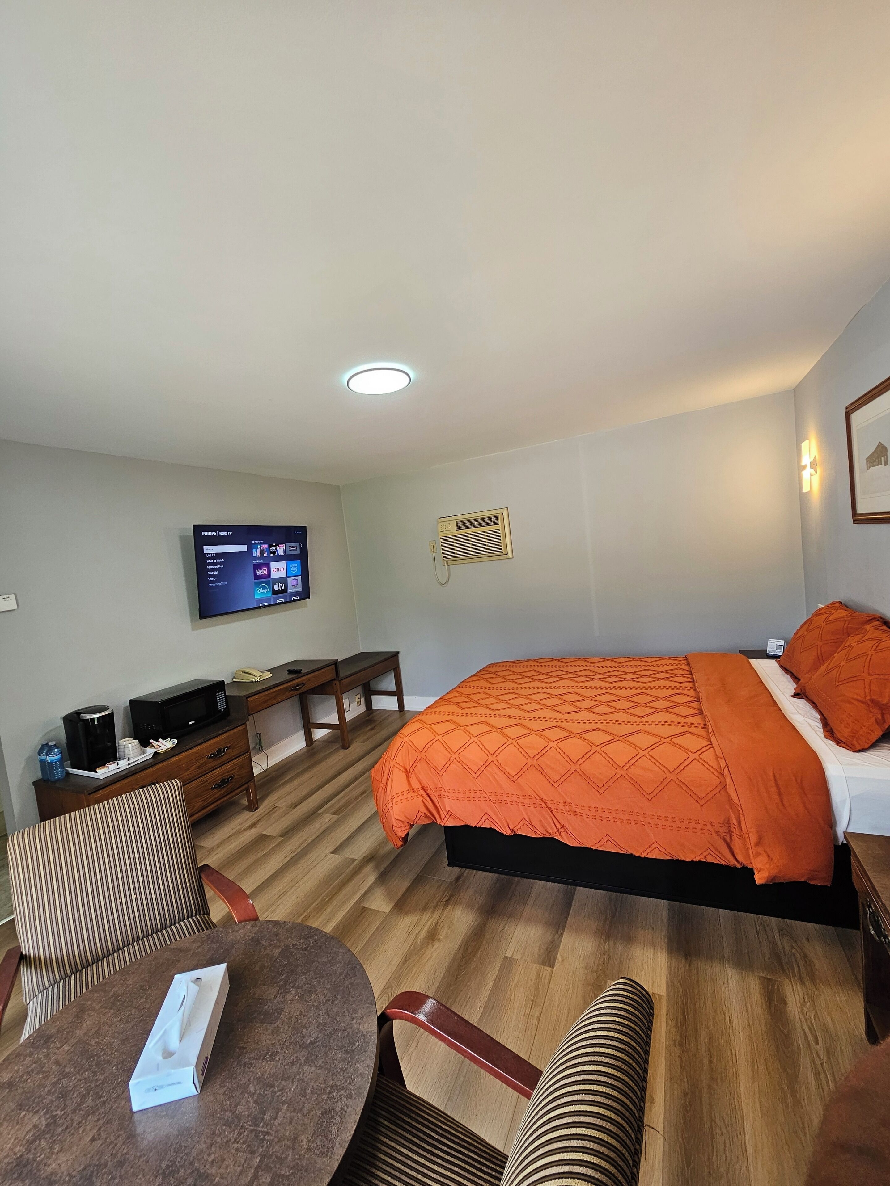 Une chambre d’hôtel équipée d’un lit, d’un bureau, d’une chaise, d’une télévision et d’une table de chevet.