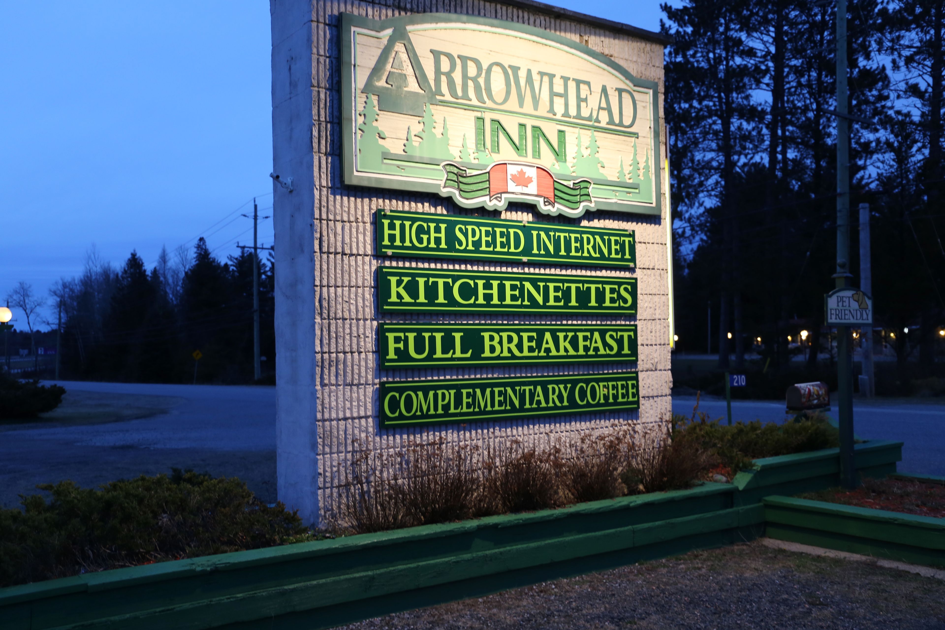 A sign for Arrowhead Inn highlighting amenities such as high-speed internet, kitchenettes, full breakfast, and complimentary coffee.