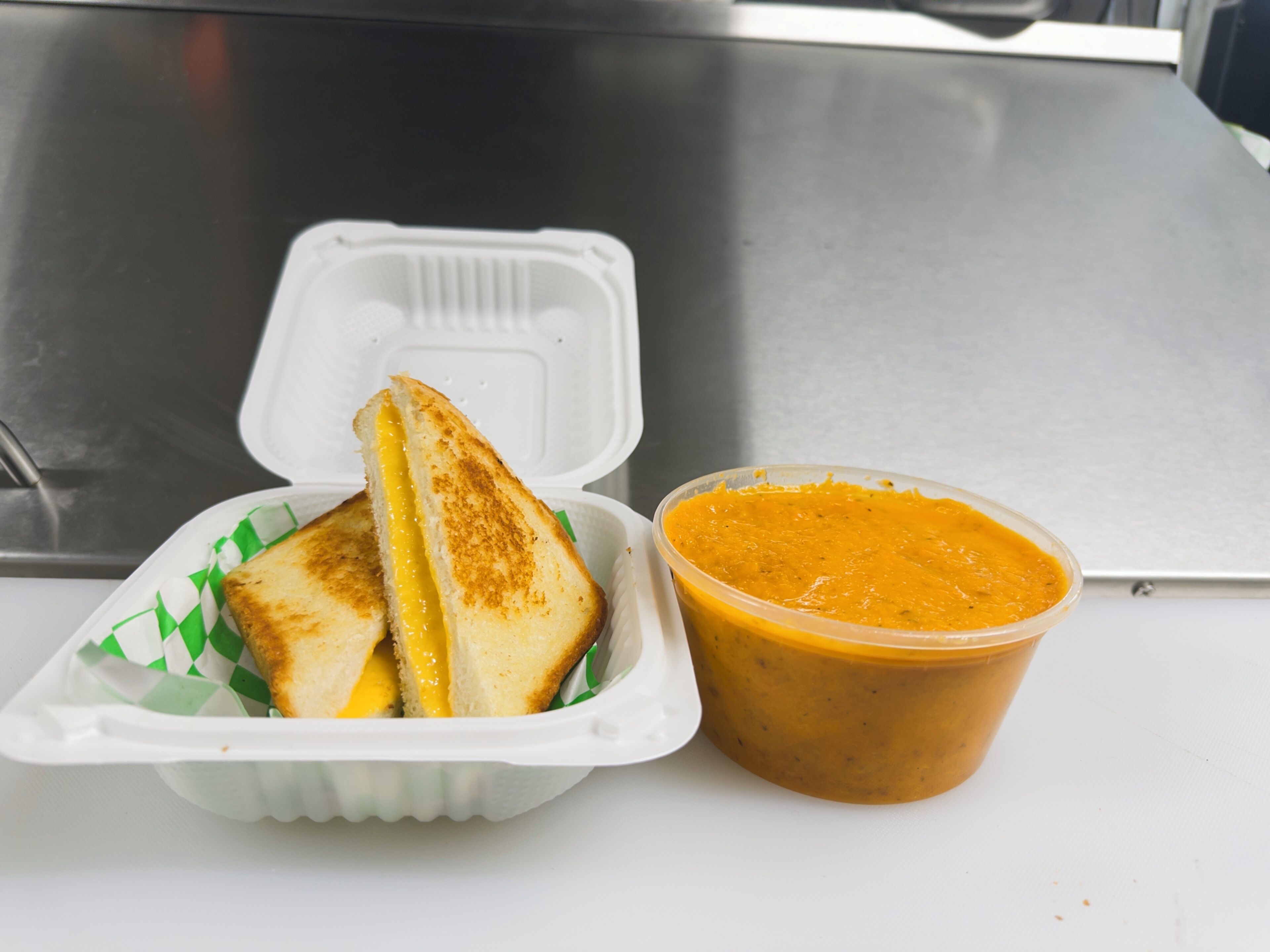 A sandwich and a bowl of soup in a white container.
