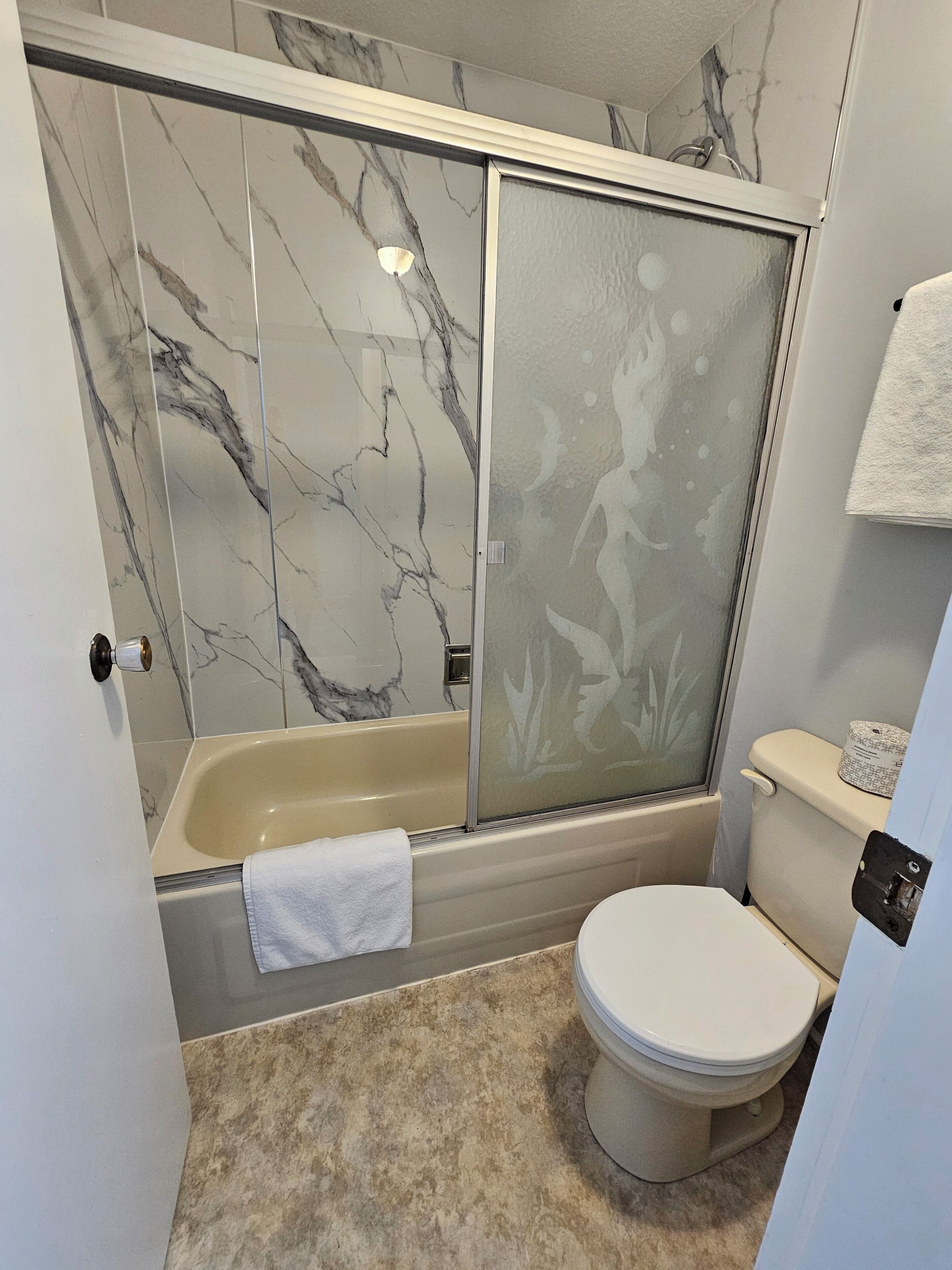 A bathroom with a bathtub, toilet, and a shower area.