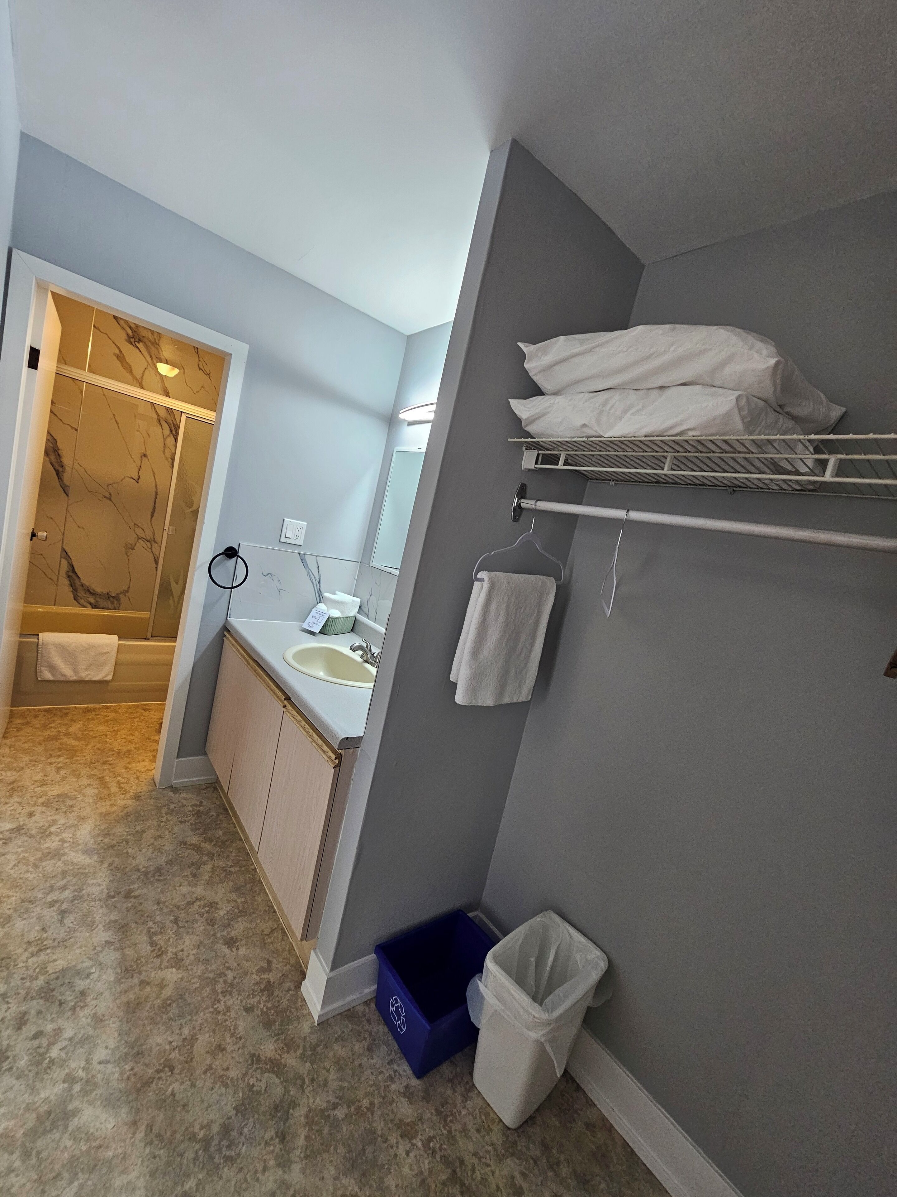 Un baño con lavamanos, espejo, toallero y zona de ducha.