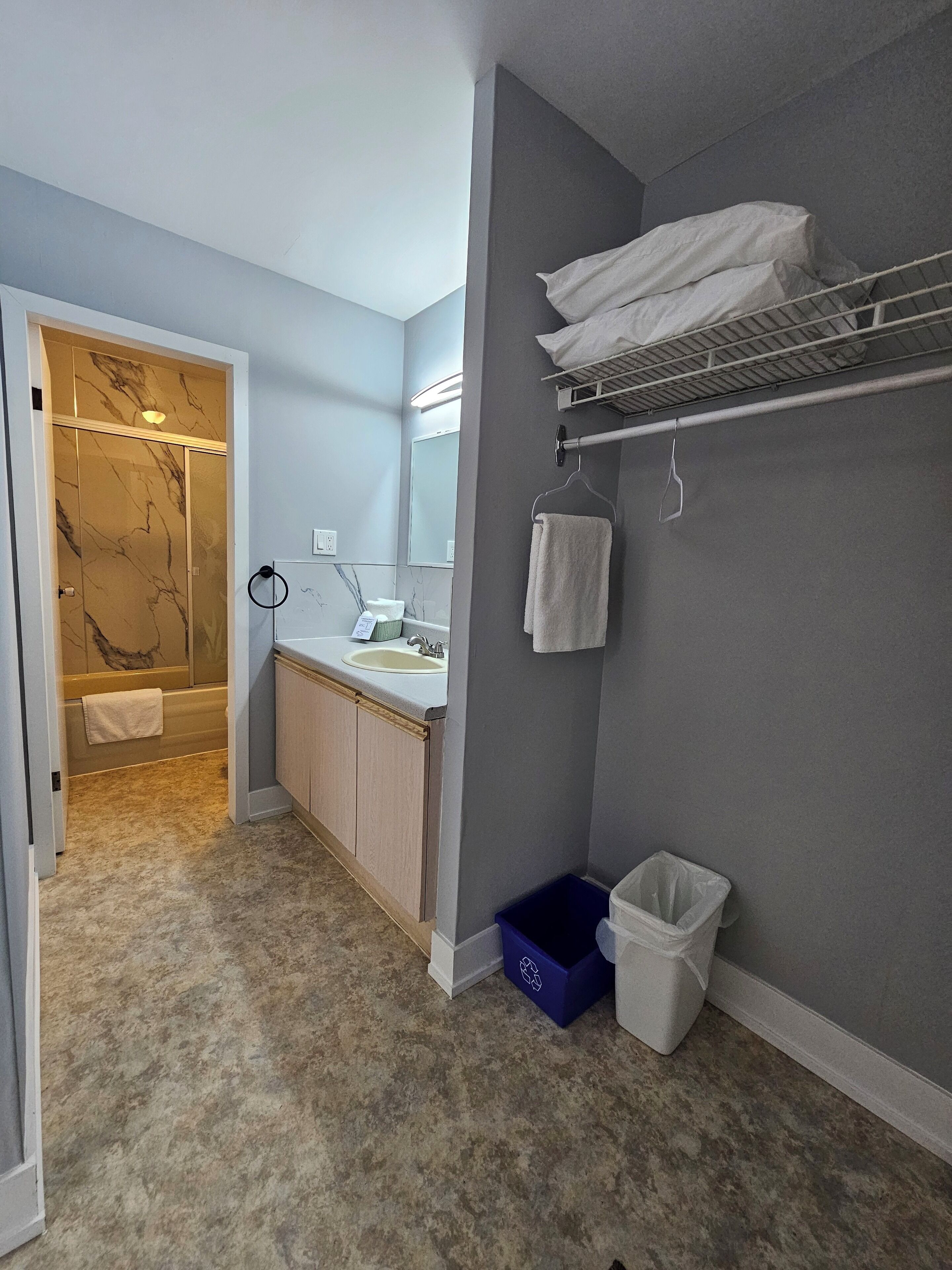 A bathroom with a marble-tiled shower, a sink with a mirror, and a towel rack.