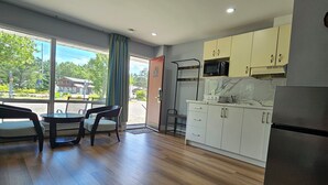 A modern kitchen with wooden flooring, white cabinets, and a stainless steel refrigerator. - Arrowhead Inn by Baaman's (Huntsville)