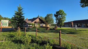 A rustic building with a sloped roof, surrounded by a fenced area with picnic tables and a signboard. - Arrowhead Inn by Baaman's (Huntsville)