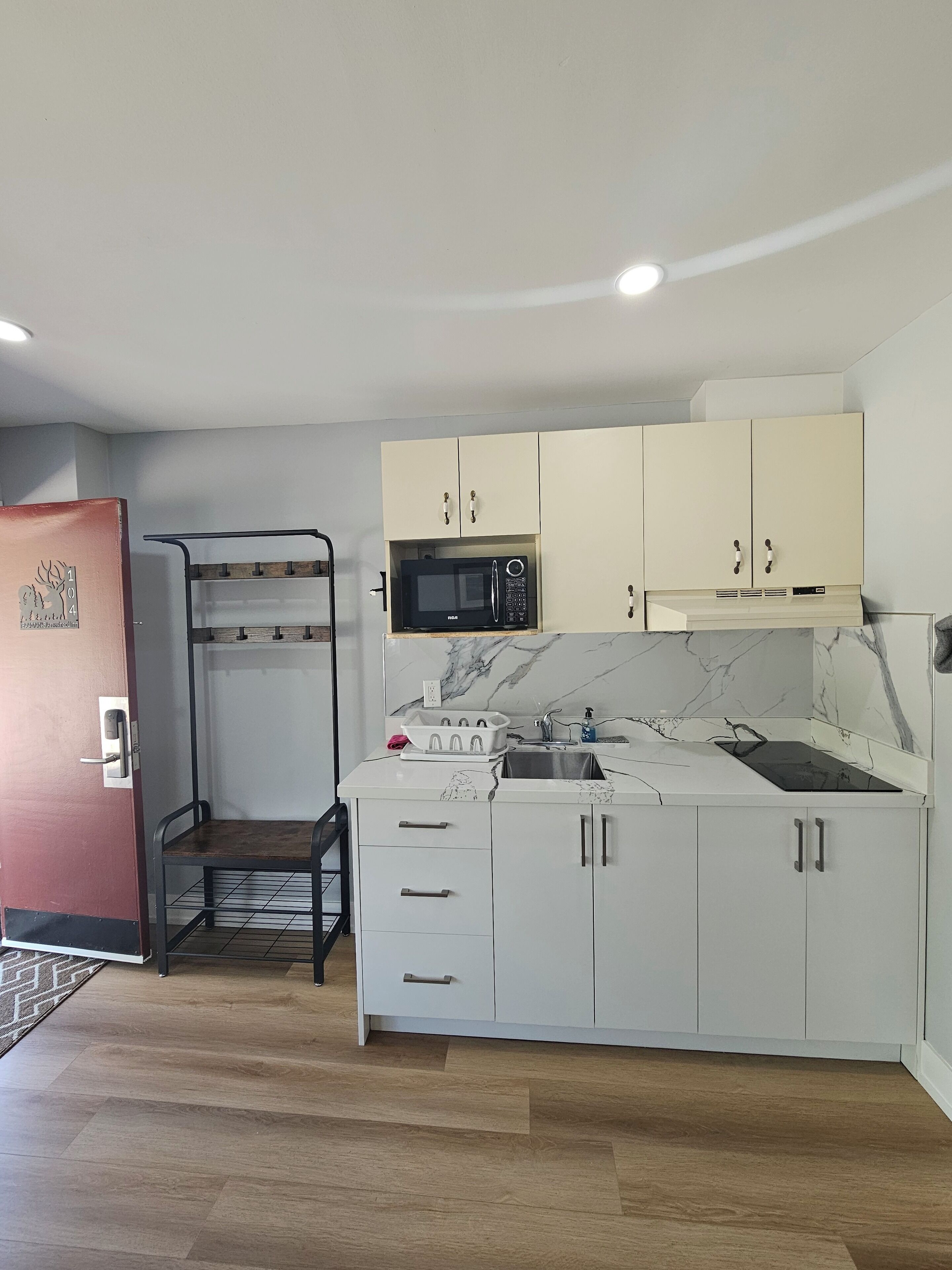 A compact kitchen with white cabinets, a microwave, a sink, and a built-in oven.