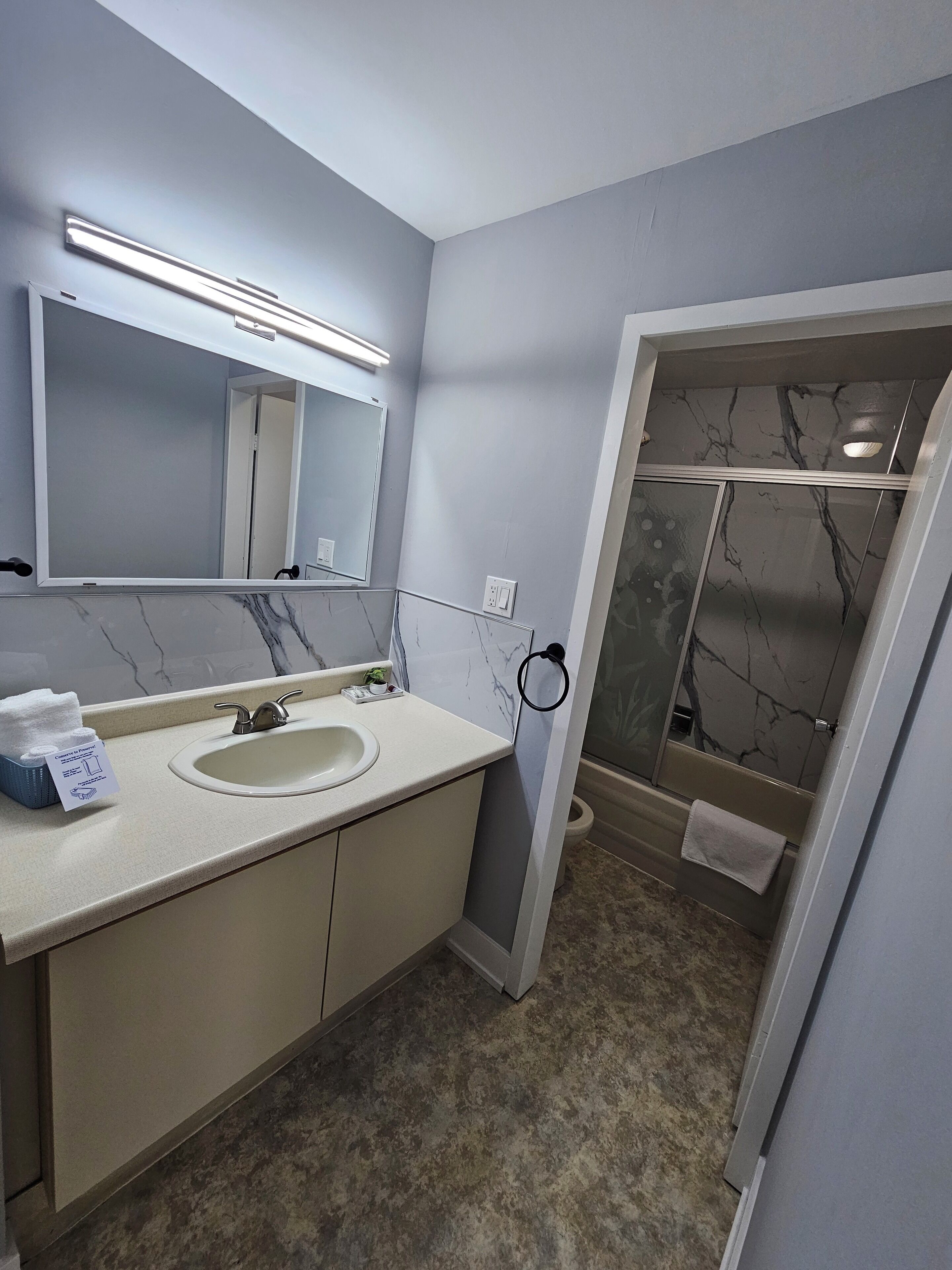 A bathroom with a double sink, a large mirror, and a shower with marble walls.