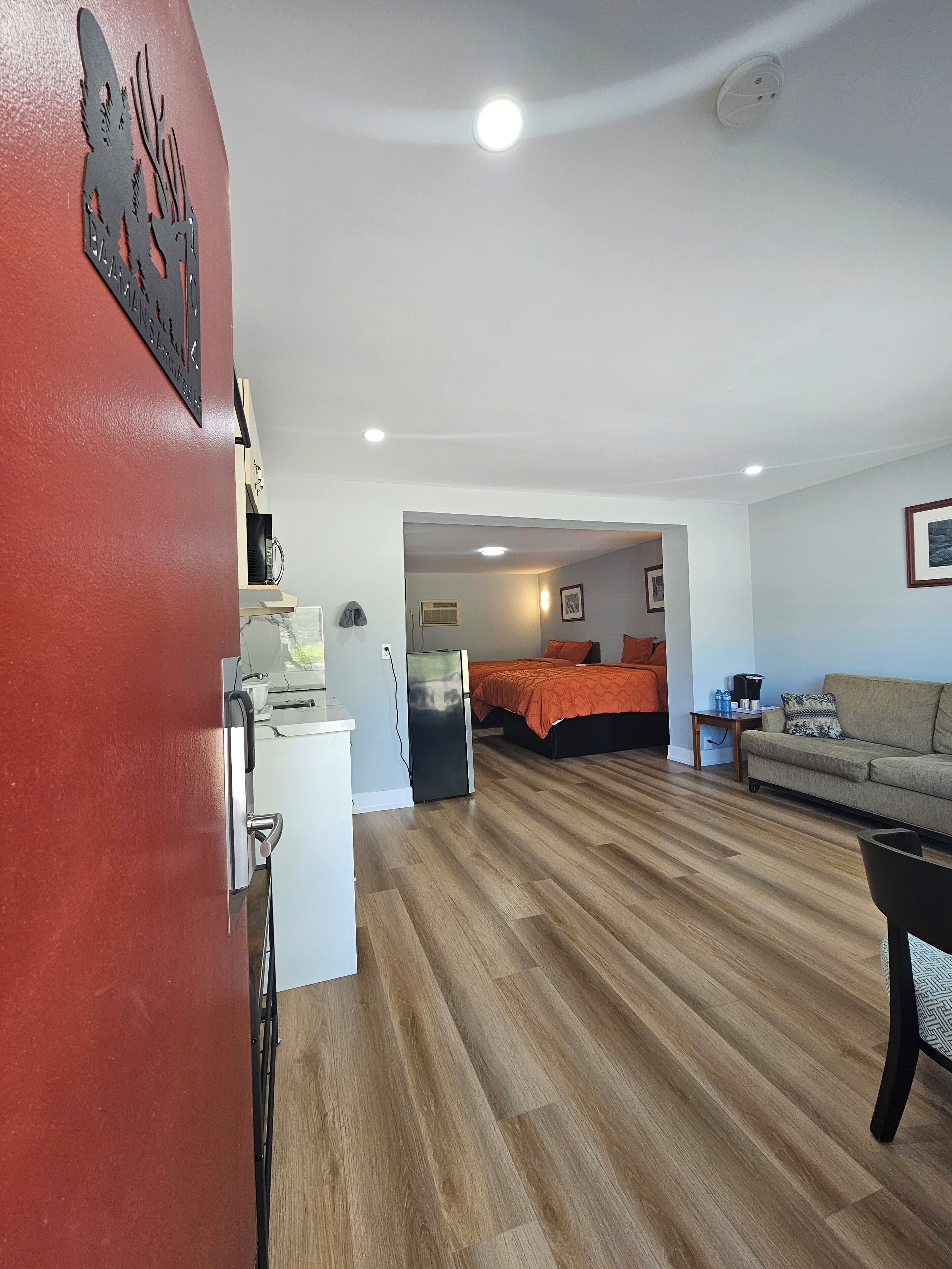 A room with a bed, a sofa, a coffee table, and a refrigerator.