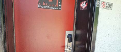Uma porta vermelha com o logotipo do Baaman's Arrowhead Inn, uma placa indicando proibido fumar e uma placa informando que aceita animais de estimação.