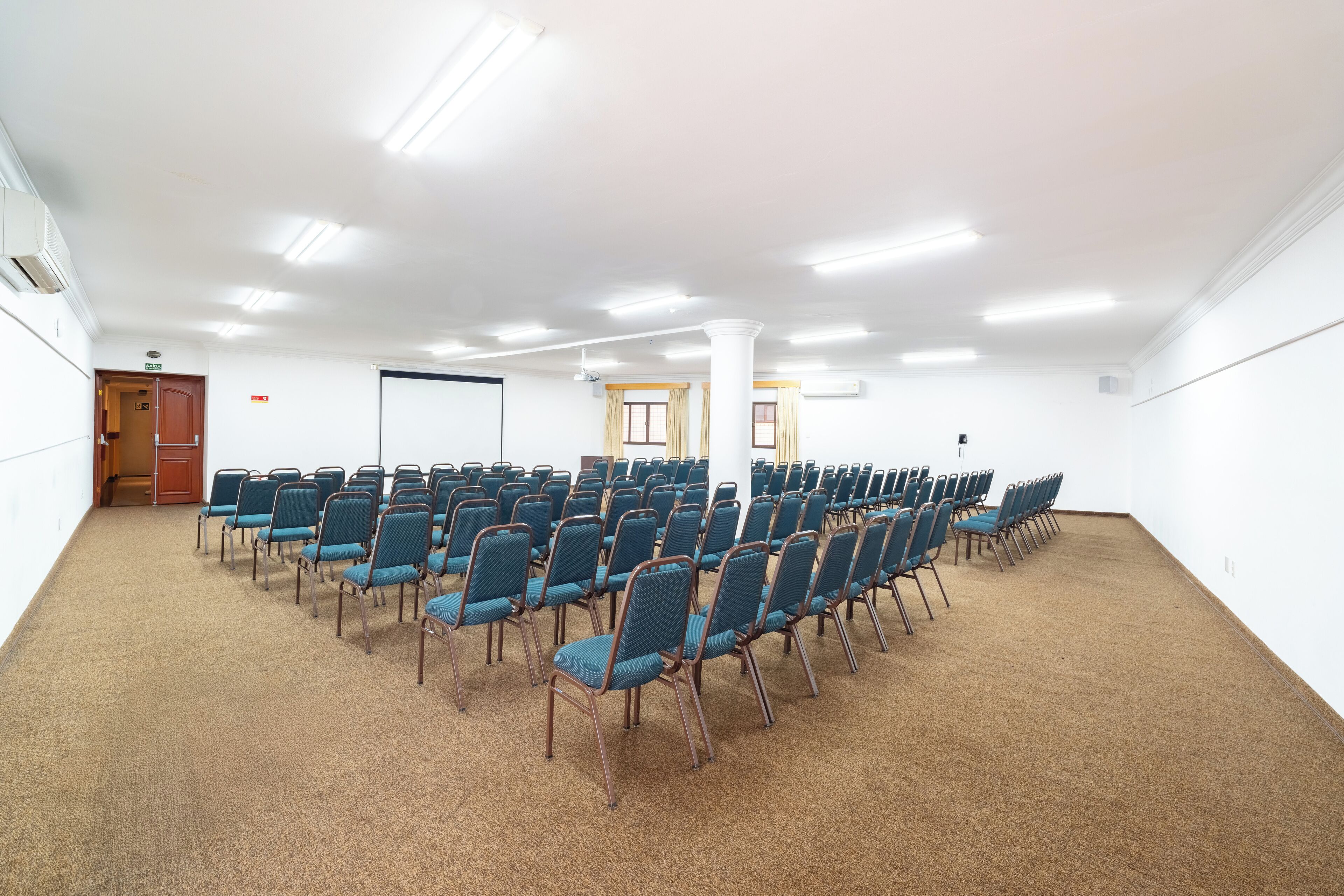 A conference room with rows of chairs, a whiteboard, and a door.