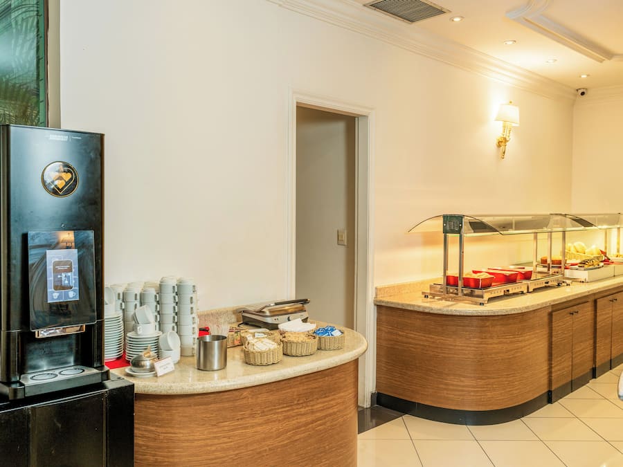 A hotel reception area with a coffee machine, a buffet counter, and a wall-mounted lamp.