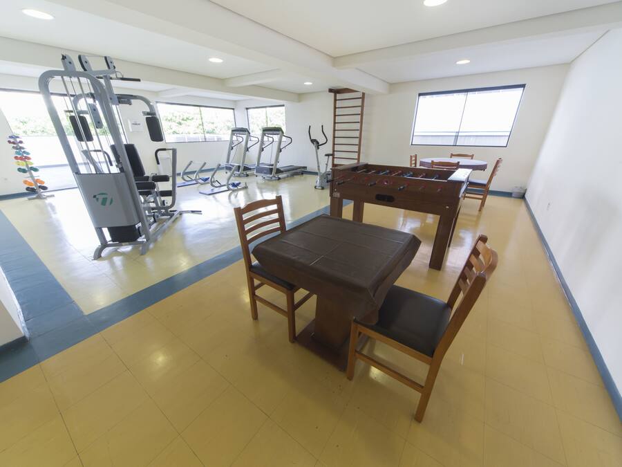Un gimnasio con equipo de ejercicio, una mesa de fútbol de mesa y una zona de comedor con sillas y una mesa.