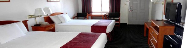 A hotel room with two beds, a desk, a chair, a television, and a door. - Sagamar Inn (Cleburne)