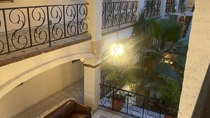 A spacious indoor courtyard with a brown leather sofa, a glass-top table with a teddy bear, and potted plants. - Hotel GYA Express (Aguascalientes)