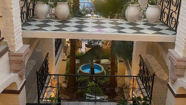 A multi-level atrium with a central fountain, tiled floors, and potted plants. - Hotel GYA Express (Aguascalientes)