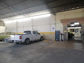 Ένα λευκό φορτηγό τύπου pick-up ήταν σταθμευμένο μέσα σε ένα κτίριο με ψηλό ταβάνι και μια κίτρινη λωρίδα ζωγραφισμένη στον τοίχο.