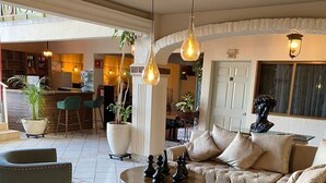 A spacious living area with a sofa, armchairs, and a coffee table. There are potted plants and hanging light fixtures. - Hotel GYA Express (Aguascalientes)