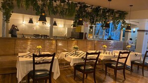 A restaurant with wooden flooring, checkered tablecloths, and dark wooden chairs. - Hotel GYA Express (Aguascalientes)