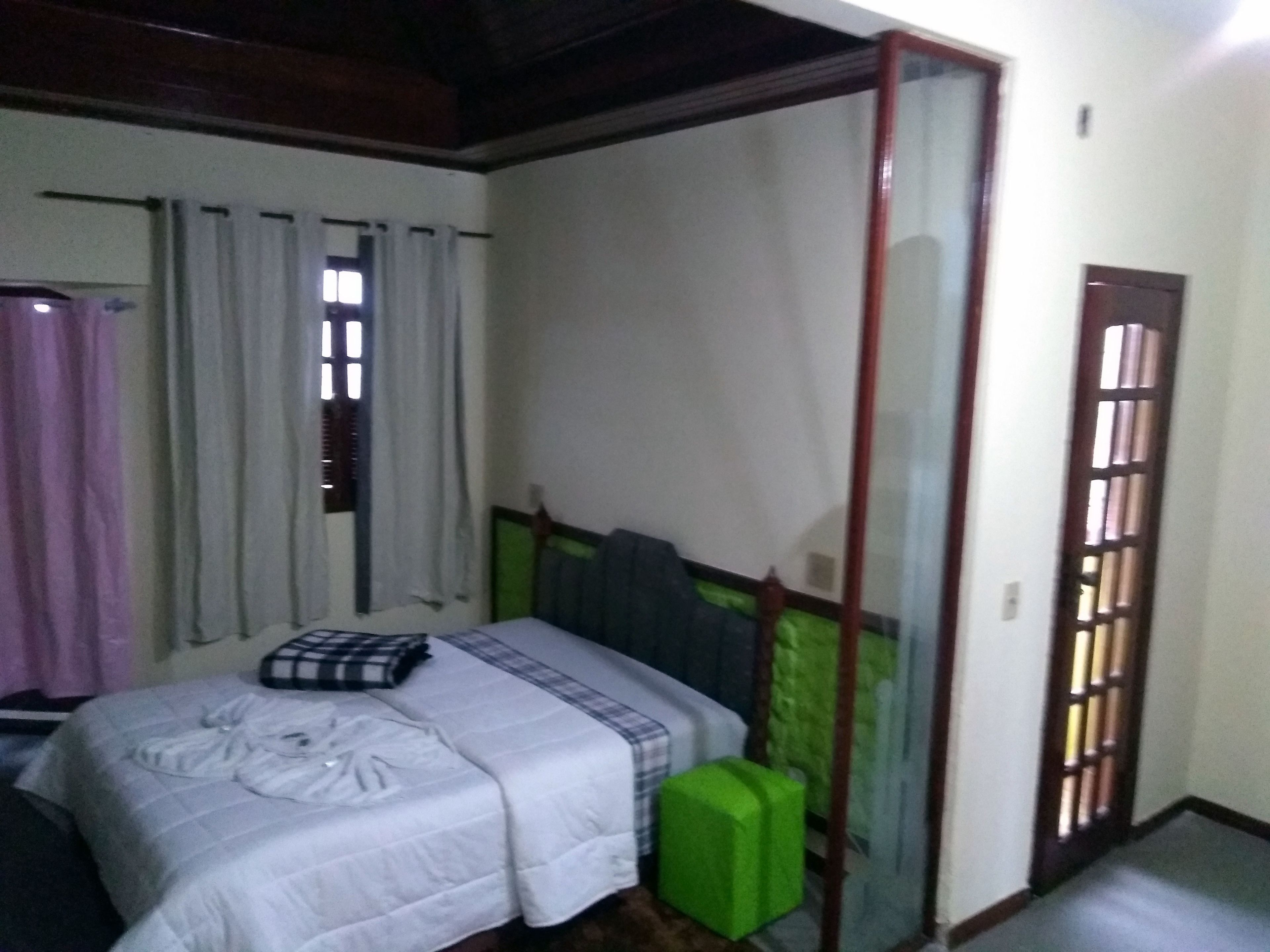 A room with a bed, a green suitcase, and a sliding glass door.