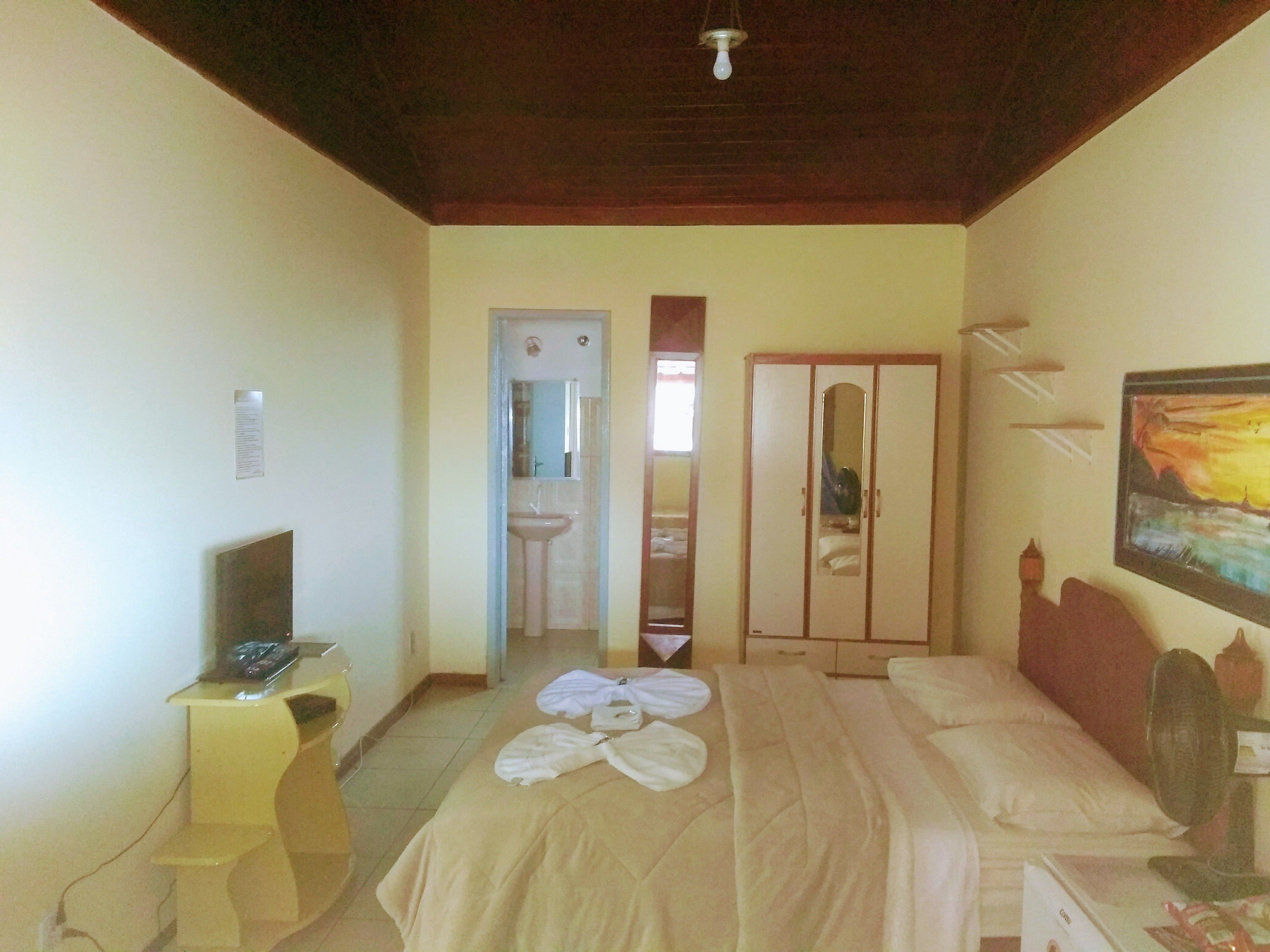 A hotel room with a bed, a desk with a computer, a wardrobe, and a painting on the wall.