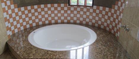 Un baño con una bañera independiente, paredes de baldosas de cuadros y una ventana que ofrece vistas.