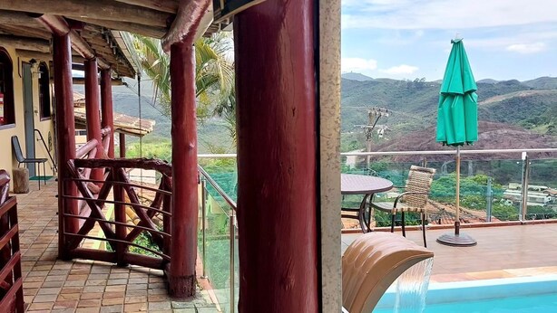 Un espacio al aire libre techado con piscina, mobiliario de madera y vistas al paisaje.